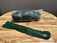 Group of tightly bundled hunter green sports socks on a wooden surface, one pair laid out flat showing length and color