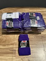 Photo shows bundled group of purple football socks with one white pair included, all packaged and labeled, on wooden surface.