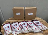 Two cardboard boxes and six pairs of Wilson soccer shin guards in original sealed plastic packaging on table.