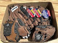 Box containing six Franklin brand gloves, mostly brown with black and grey accents, some with tags