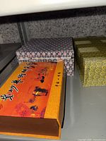 Three decorative boxes on shelf: orange lid box, blue-white geometric box, yellow-green hex pattern box