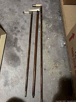 Three walking sticks laid on the floor showing full length and wooden shafts.