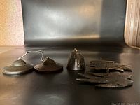 Photo showing five metal items including round cymbals with chain, small bell, and bird-shaped metal ornaments