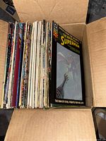 Box full of assorted comic books showing full side view of spines in a cardboard box.
