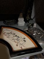 Photo showing the carved soapstone figurine, black lacquer vase with floral inlay, metal boxes with intricate cloisonné-style designs, and a framed hand-painted porcelain plaque with Chinese figures and calligraphy.