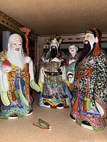 All three Chinese porcelain figurines displayed together on a shelf.