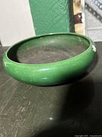 Top and side view of the green glazed ceramic bowl showing smooth finish and rounded edges.