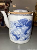 Side view showing ornate blue dragon design on white porcelain body of teapot with bamboo handle on top and ceramic spout visible