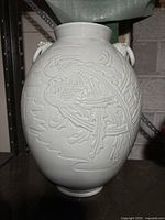 Full-view of vase showing bulbous body, flared rim, relief carving of phoenix and clouds