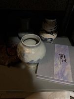Vases and book arranged on shelf, front view