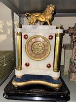 Full front view of marble mantel clock with brass columns, lion finial, base and front dial