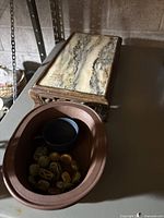 Photo showing stone box with marble-like top, dark cup inside a brown tray, and carved bead bracelet within the tray.