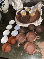 Overview of all teacups and trays on a dark surface showing variety and condition.