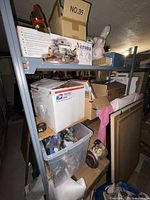 Front left side view of the metal shelving unit displaying the content stored (not included in lot). Shows condition and structure of shelf.