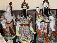 Set of three large Chinese porcelain figurines on display shelf, showing overall size and color