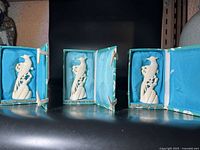 Three Chinese bird carvings, each in own turquoise fabric-lined box on black surface.