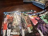 Photo showing a stack of 9 Batman comic books with vibrant covers featuring Batman and Catwoman among others.