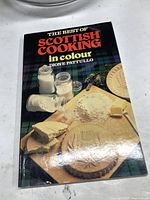 Front cover of The Best of Scottish Cooking cookbook showing a tartan background and baking ingredients.