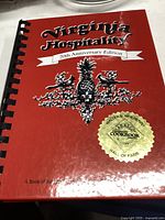Photo of the front cover of the Virginia Hospitality 20th Anniversary Edition cookbook with decorative elements and hall of fame seal.