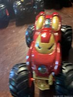Front angled view of large monster truck toy with Iron Man themed red and gold paint and oversized black tires.