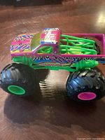 Side view of the large monster truck toy showing pink, green, and zebra stripe design with large wheels.