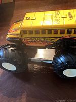 Side view of large yellow Hot Wheels monster truck toy with flame decals, number 23, and big black tires.
