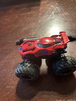Side-angle view of the Spider-Man monster truck toy showing the detailed Spider-Man face design on top and large black plastic tires.