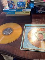 Photo of the yellow vinyl record on a table alongside the album cover sleeve, showing the title and Elvis Presley image on the front cover.
