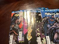 Six Batman comics arranged fanned out on a table showing various covers
