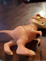 Photo showing the brown stretchy T. rex toy with textured details, large eyes, and teeth.