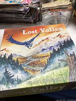 Box cover of Lost Valley Goldrush, showing illustrated eagle flying above a mountainous valley landscape.