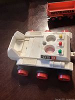 Top view of the white vintage space trailer toy with US 8 label and colored buttons on top, red wheels.