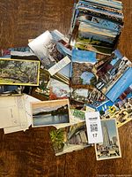 Overview of a collection of postcards spread out on a table showing various US landmarks, nature scenes, and city views. Some postcards show backs with postage stamps and handwritten text.