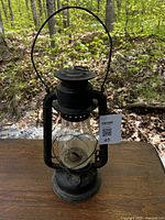 Full view of the black metal coal oil lantern with glass globe and metal handle, showing overall condition and rust spots.