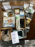 Wide view of the box containing multiple small boxes and bags of screws and fasteners in different sizes and packaging showing labels and brands