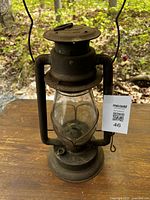 Front view of a vintage metal coal oil lantern with glass globe, showing overall condition, metal frame, and handle.