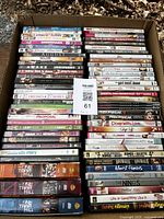 Photo showing a large assortment of DVDs stacked in a cardboard box, including movie and TV series titles.