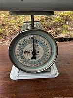 Close-up of the front dial of the vintage Hanson nursery scale showing weight measurement numbers and decorative crane images.