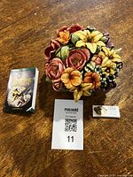 Photo showing Lord Byron's Harmony Garden box alongside the floral bouquet figurine and a MaxSold bid card.