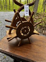 Front and side view of the hand carved wooden magazine rack showing circular woven wood components and bent wood frame.