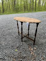 Solid wood sofa table displayed outdoors on gravel, showing the entire table and turned leg design.