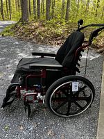 Side angle showing red frame, large black rear wheel, Roho seat cushion and padded armrest.