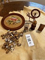Full view of lot items including hooked rug, miniature spinning wheel, wooden spindles, and other miniatures on a soft beige surface