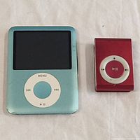 Photo showing blue iPod Classic and red iPod Shuffle side by side on white surface.