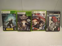 Four video game cases including Xbox 360 and PlayStation 2 titles arranged side by side.