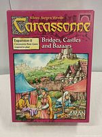 Front of Carcassonne Expansion 8 box showing title Bridges, Castles and Bazaars, artwork and branding.