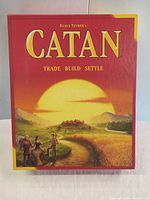 Front of box with iconic CATAN artwork showing settlers and landscape.