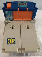 Playset top view showing blue and orange components, fold-down beige numbered panels with '32'.