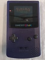 Purple Nintendo Game Boy Color console powered on with Pokémon Silver Version game displayed on screen.
