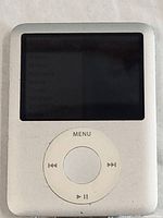 Front view of iPod Nano showing the screen and click wheel, screen is on with menu partially visible.
